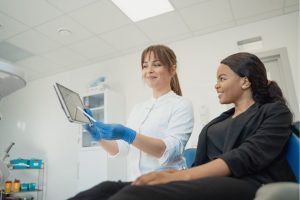 A dentist showing the patient how to set up an appointment on a tablet.