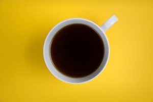a closeup photo of a cup of coffee against a yellow background