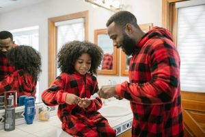 a photo of a father and his daughter brushing their teeth